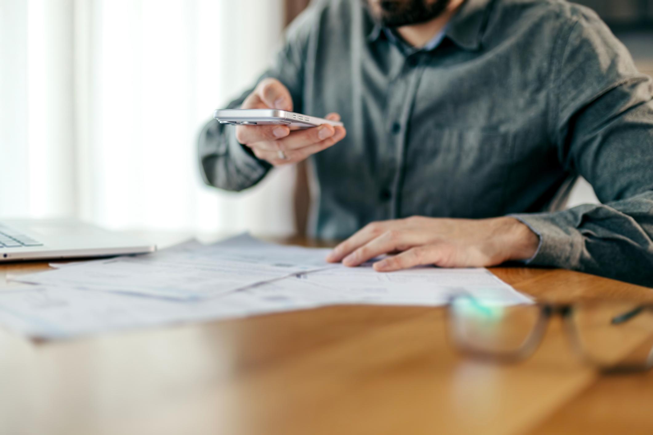 Person scanning flat document using smartphone in daylight